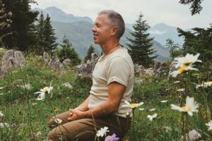 Seitenaufnahme von Yogalehrer Pascal Portmann in blühender Almwiese in den Bergen der Schweiz